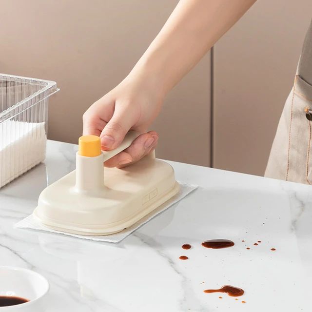 Cleaning brush wiping spills from a kitchen countertop